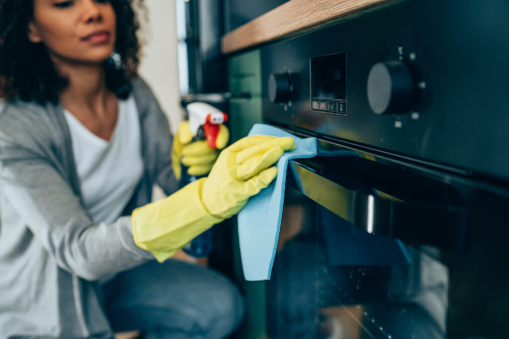 Black woman wiping surface of an oven